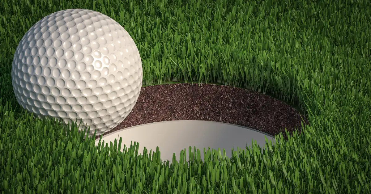 A golf ball about to fall in the hole